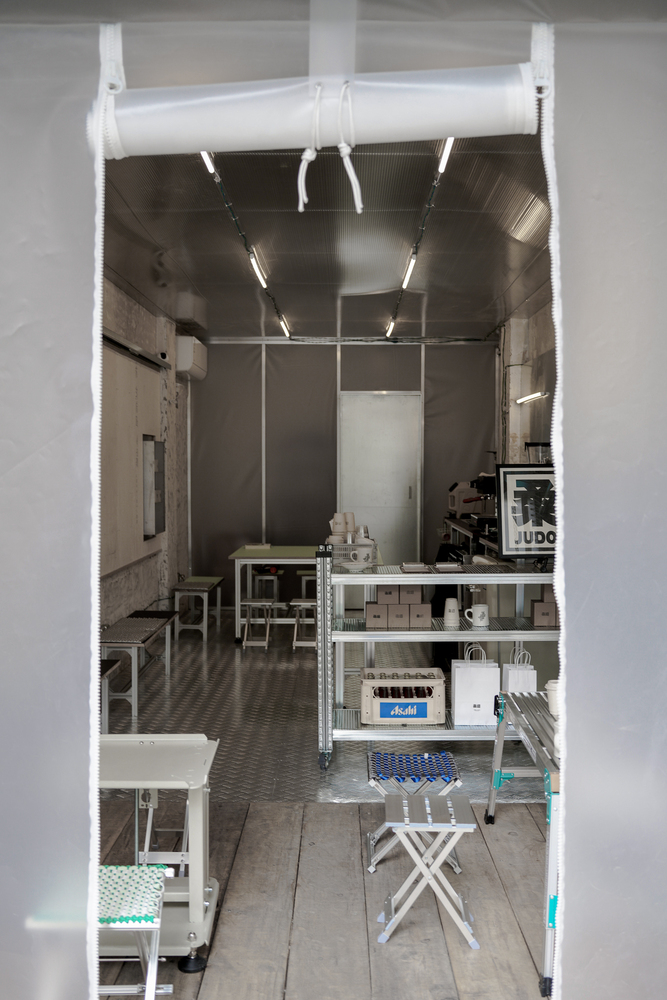 Interior workspace with metal shelving units and a cylindrical white duct suspended from the ceiling