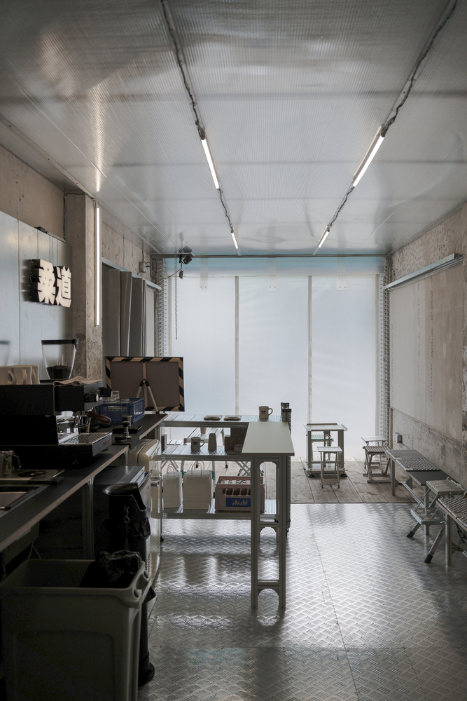 Long view of workshop interior with linear fluorescent lighting and translucent roller shades at the entrance