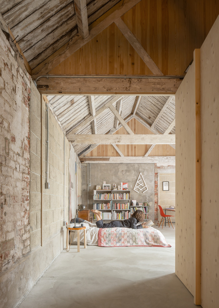 View through doorway into living space with exposed timber trusses and white brick walls