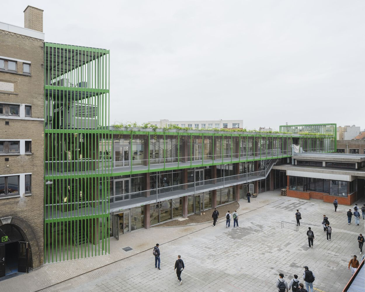 Elevated view of the paved courtyard surrounded by green louvered facade and planted rooftop