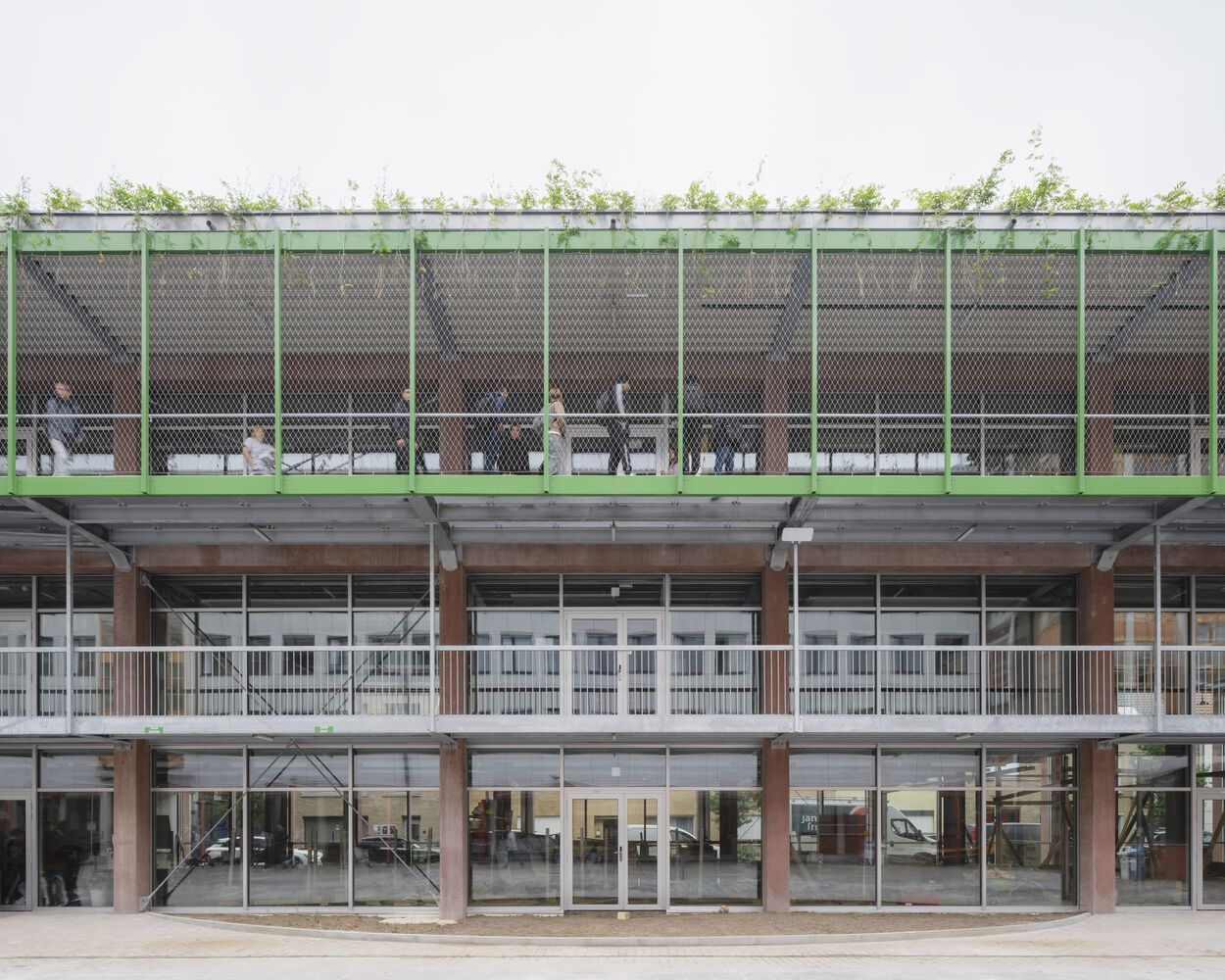 Facade elevation showing green mesh screen with planted roof above glazed levels and timber columns