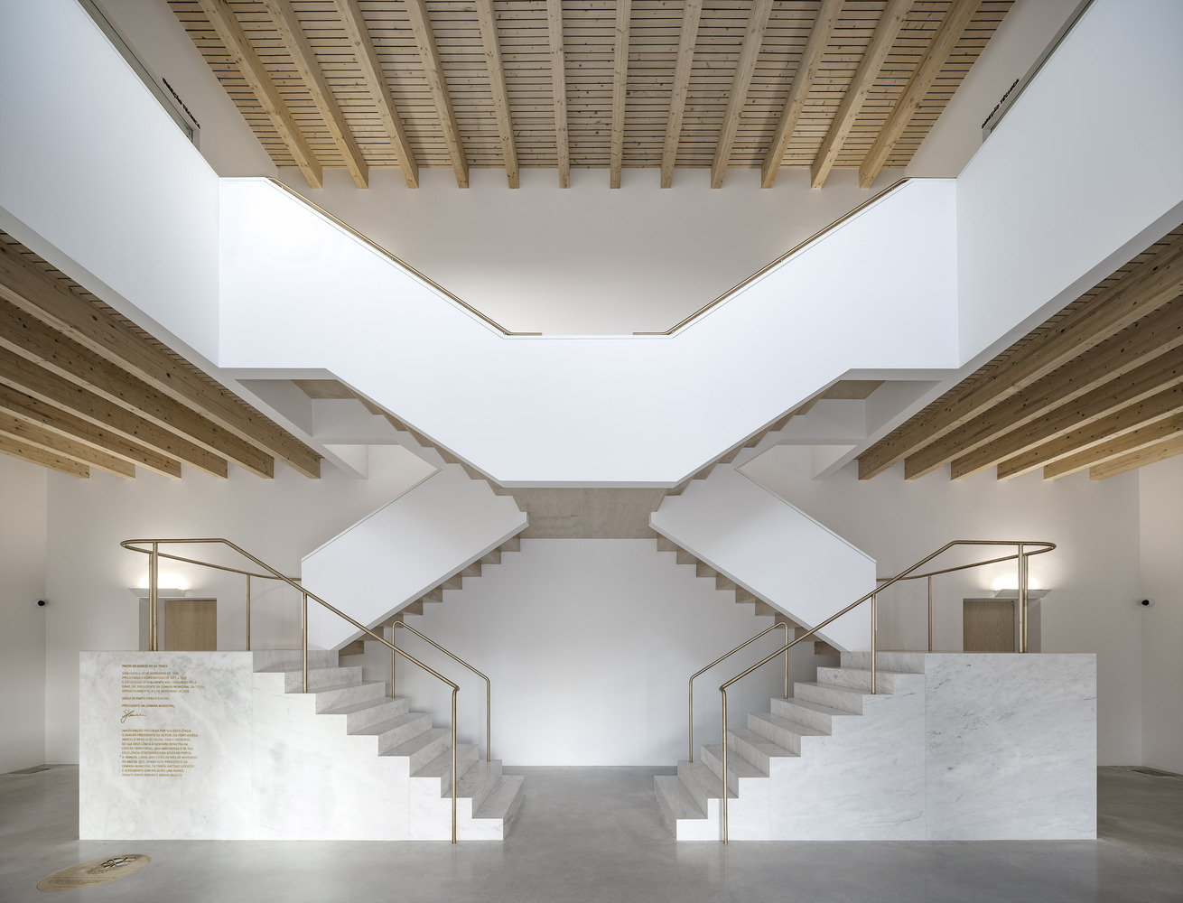 Symmetrical white marble staircases rising beneath timber slatted ceiling and clerestory windows