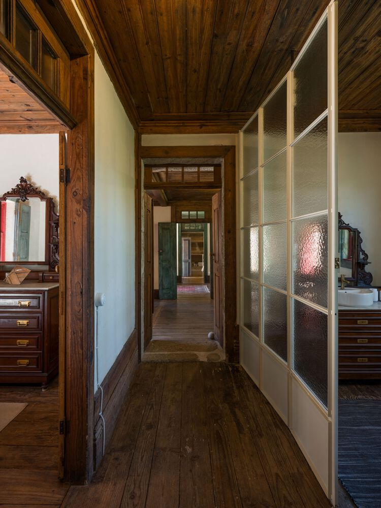Hallway with timber plank ceiling and textured glass partition wall flanked by dark wood flooring