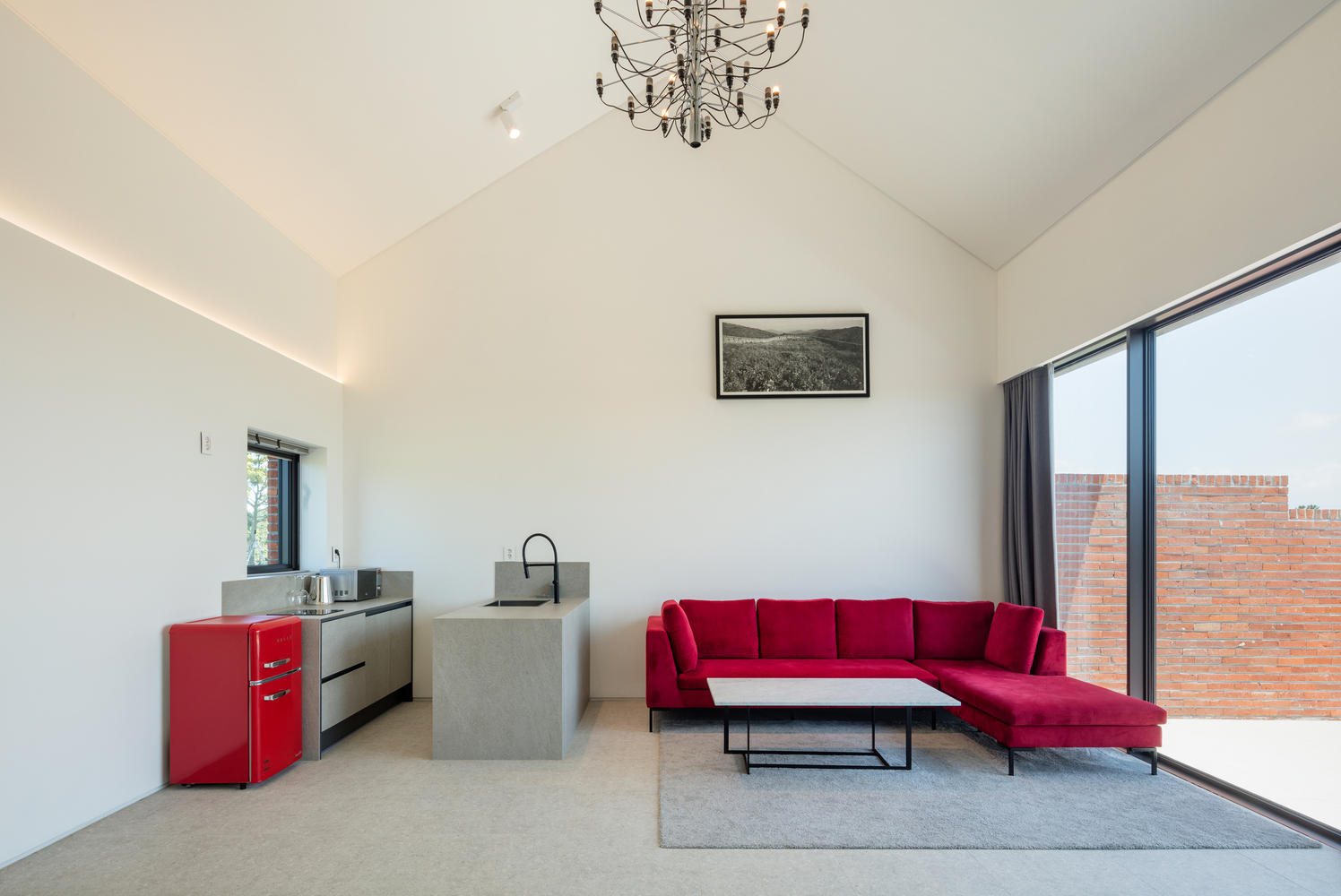 Open living space with vaulted ceiling and full-height glazing overlooking the brick courtyard