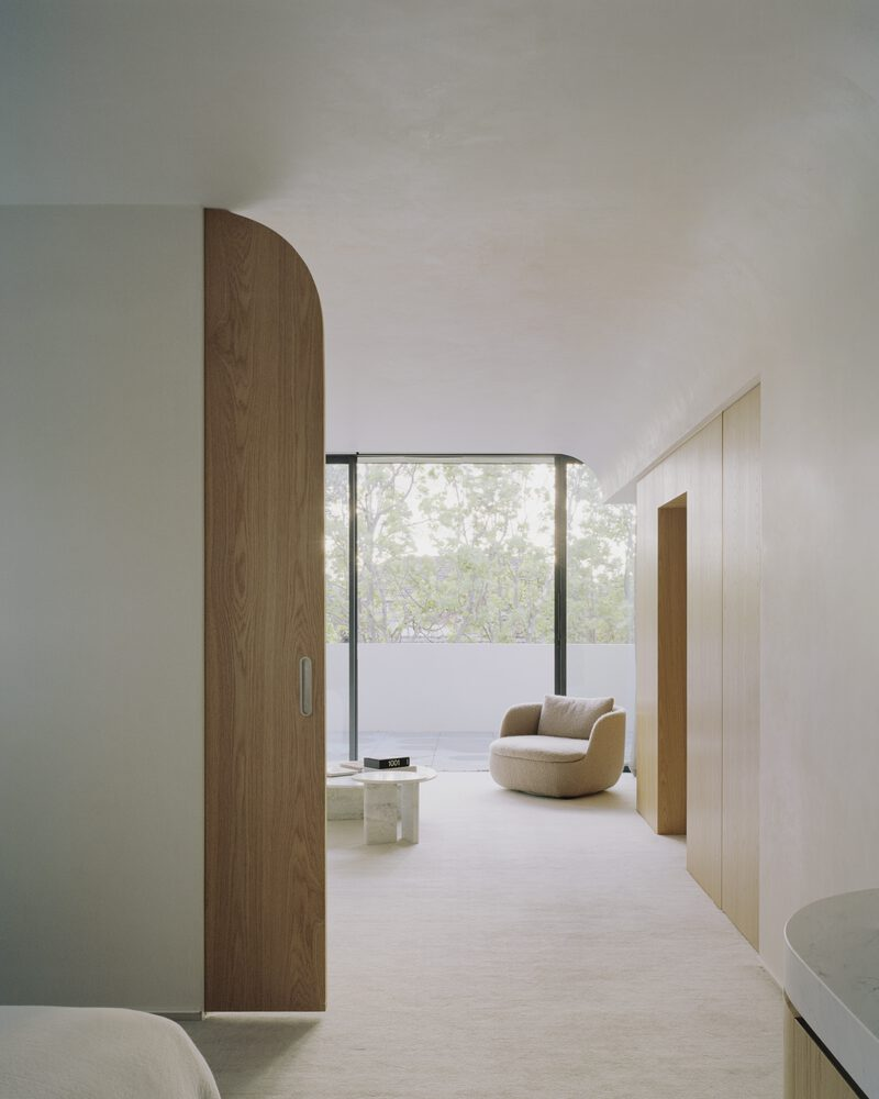 Corridor with curved timber partition wall and terrace view through floor-to-ceiling glazing