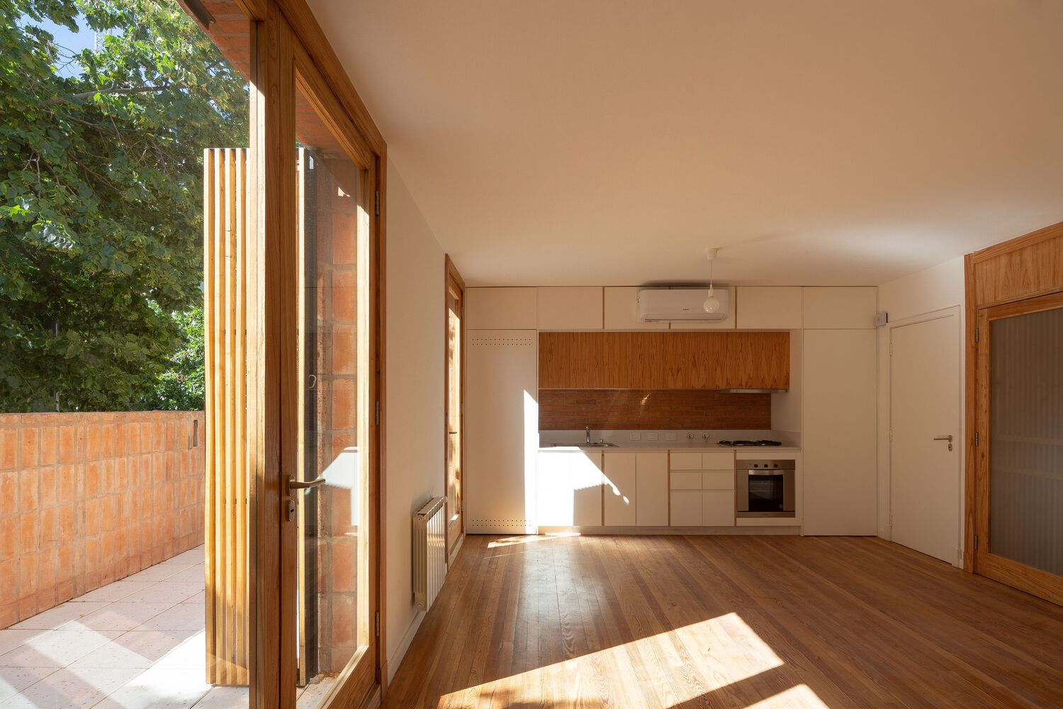 Open plan kitchen and living space with timber flooring and vertical timber battens at the glazed doors