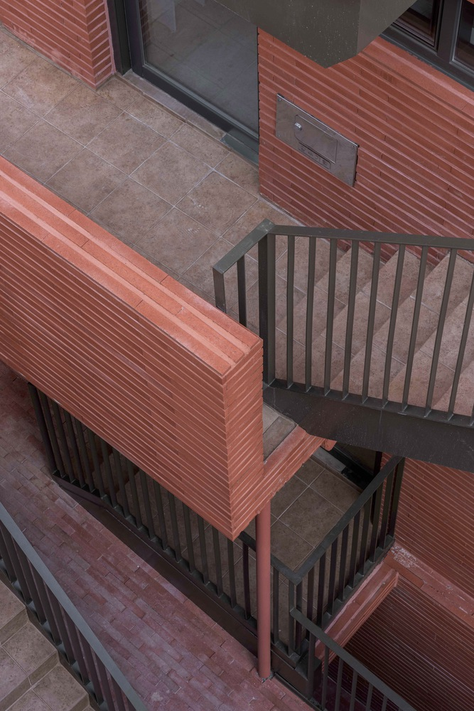 Overhead view of zigzag exterior stair with red brick walls and metal railings