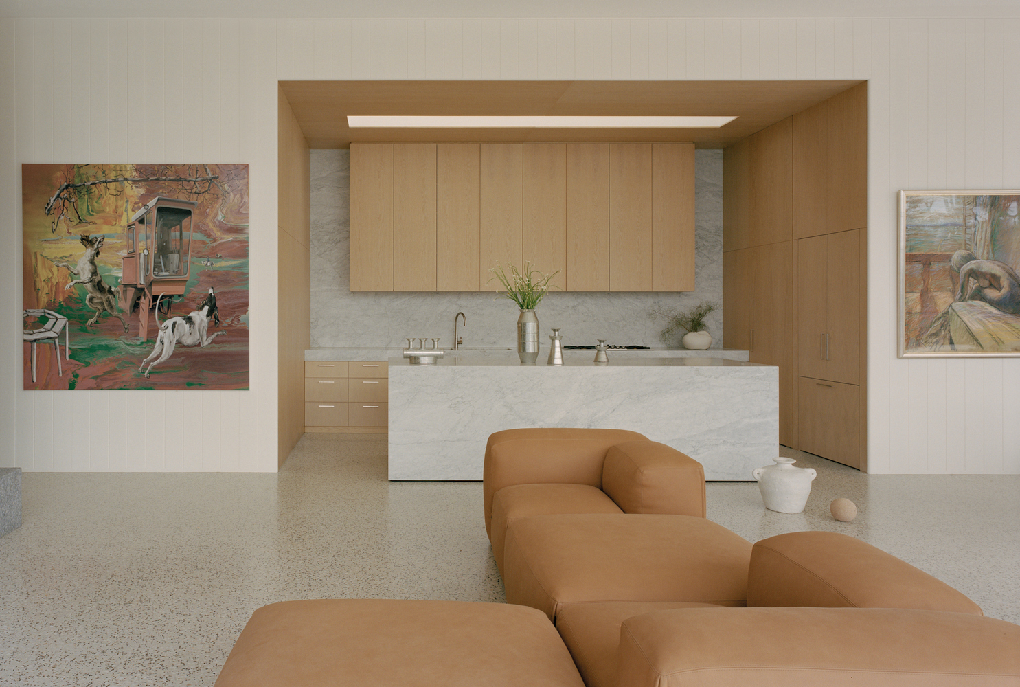 Open-plan living space with marble kitchen island and timber cabinetry under recessed ceiling lighting