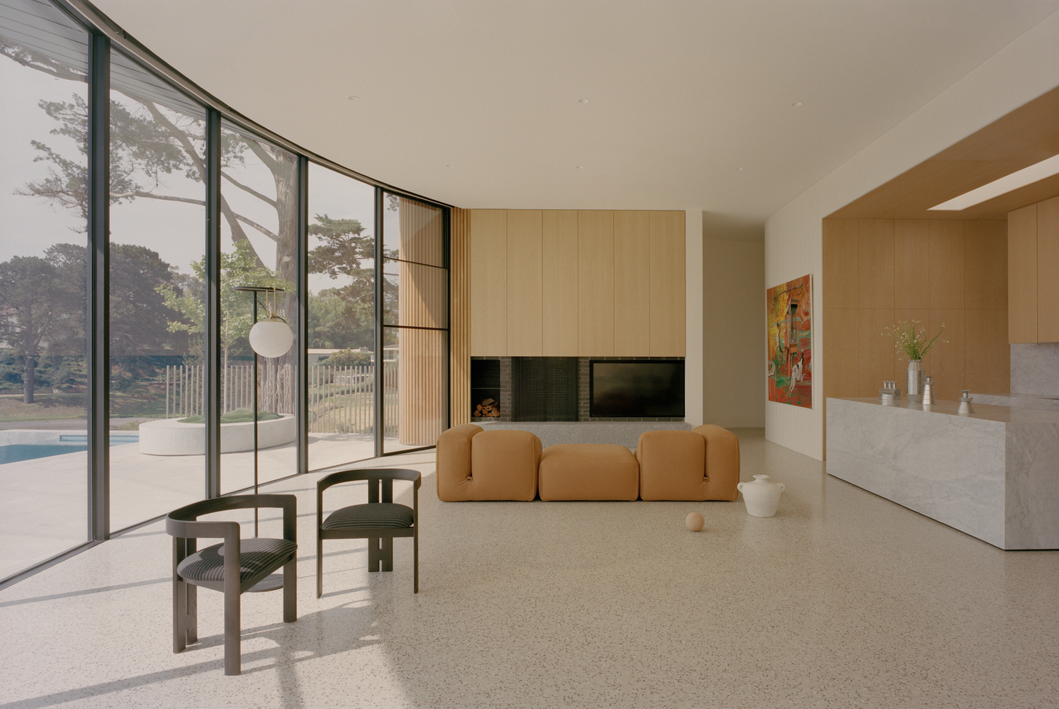 Living room with floor-to-ceiling glazing opening to pool terrace and timber cabinetry wall