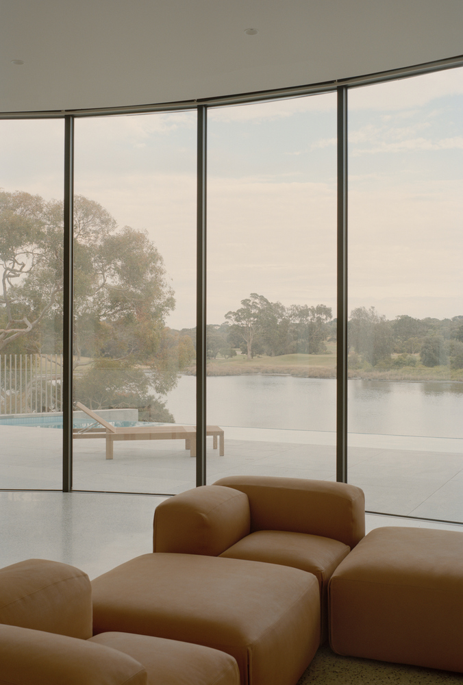 Corner window overlooking terrace with chaise and distant lake through slim black frames