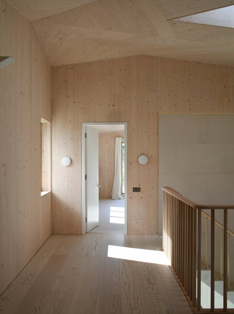 Upper landing with light wood paneling and flooring showing doorway with sunlight streaming through