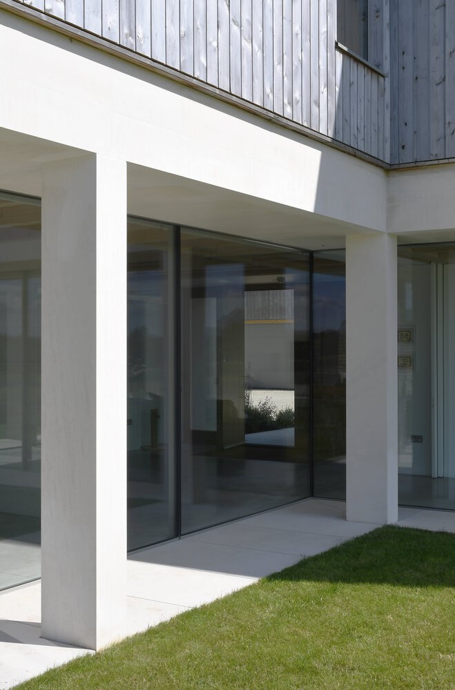 Covered porch with white rendered columns and dark sliding glass doors leading to the interior