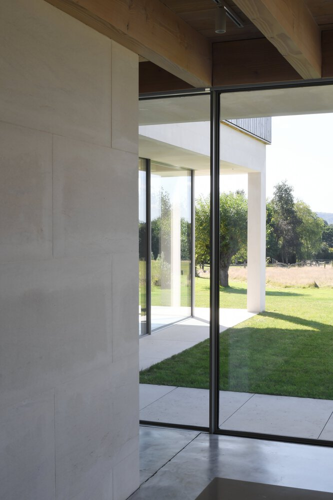 Full-height glazed corner pivot door opening to garden lawn with timber soffit above