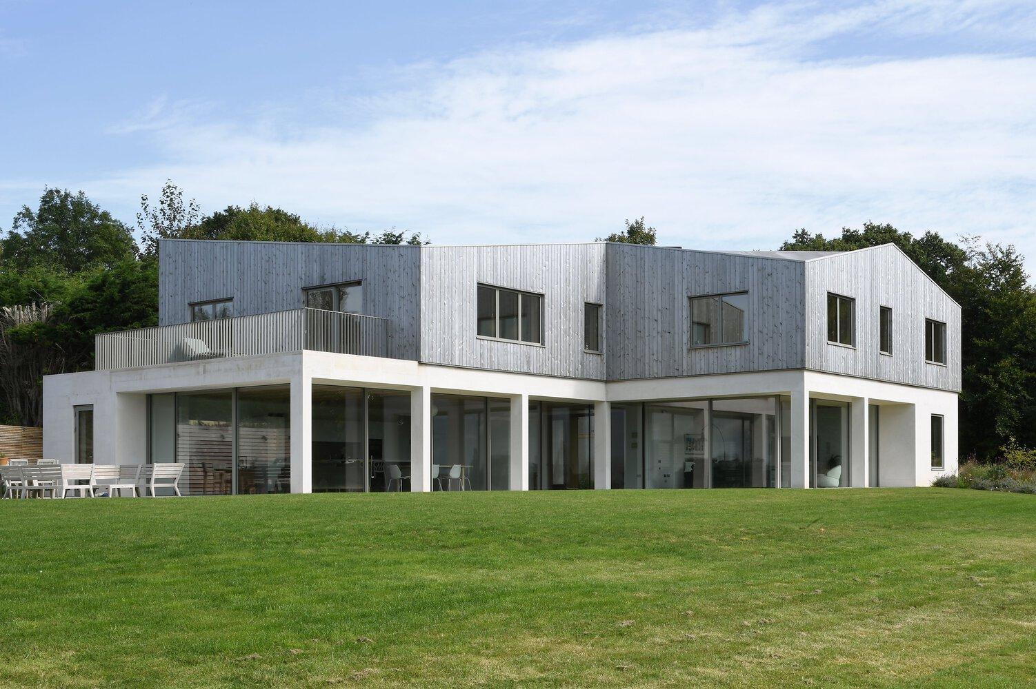 Garden elevation showing a two-storey volume clad in vertical timber boarding above white ground floor walls