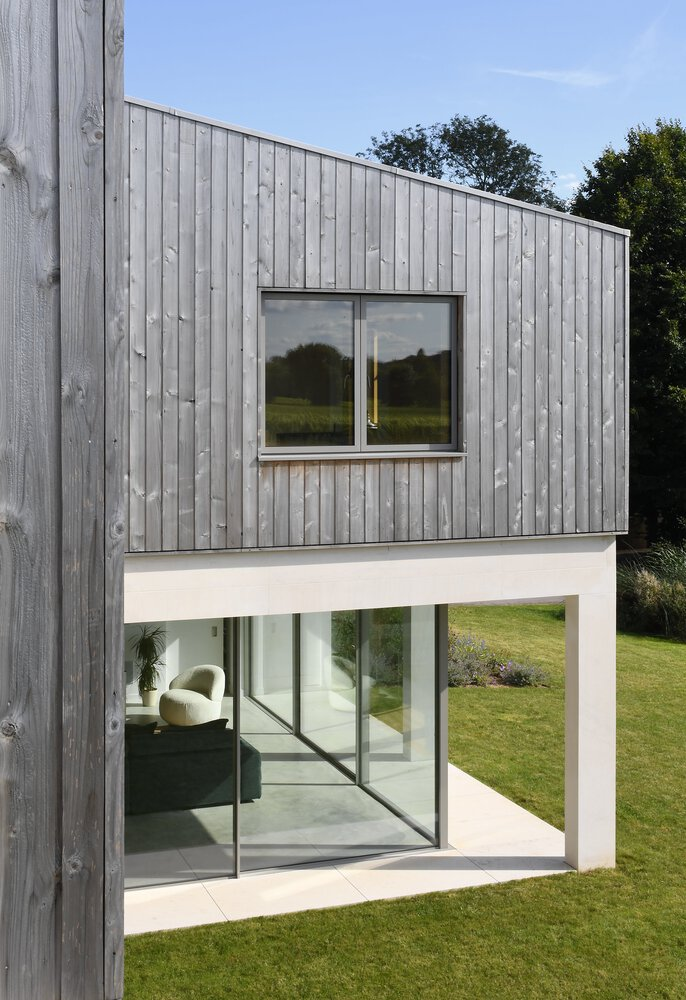 Vertical timber cladding above white rendered base with sliding glass doors opening to lawn