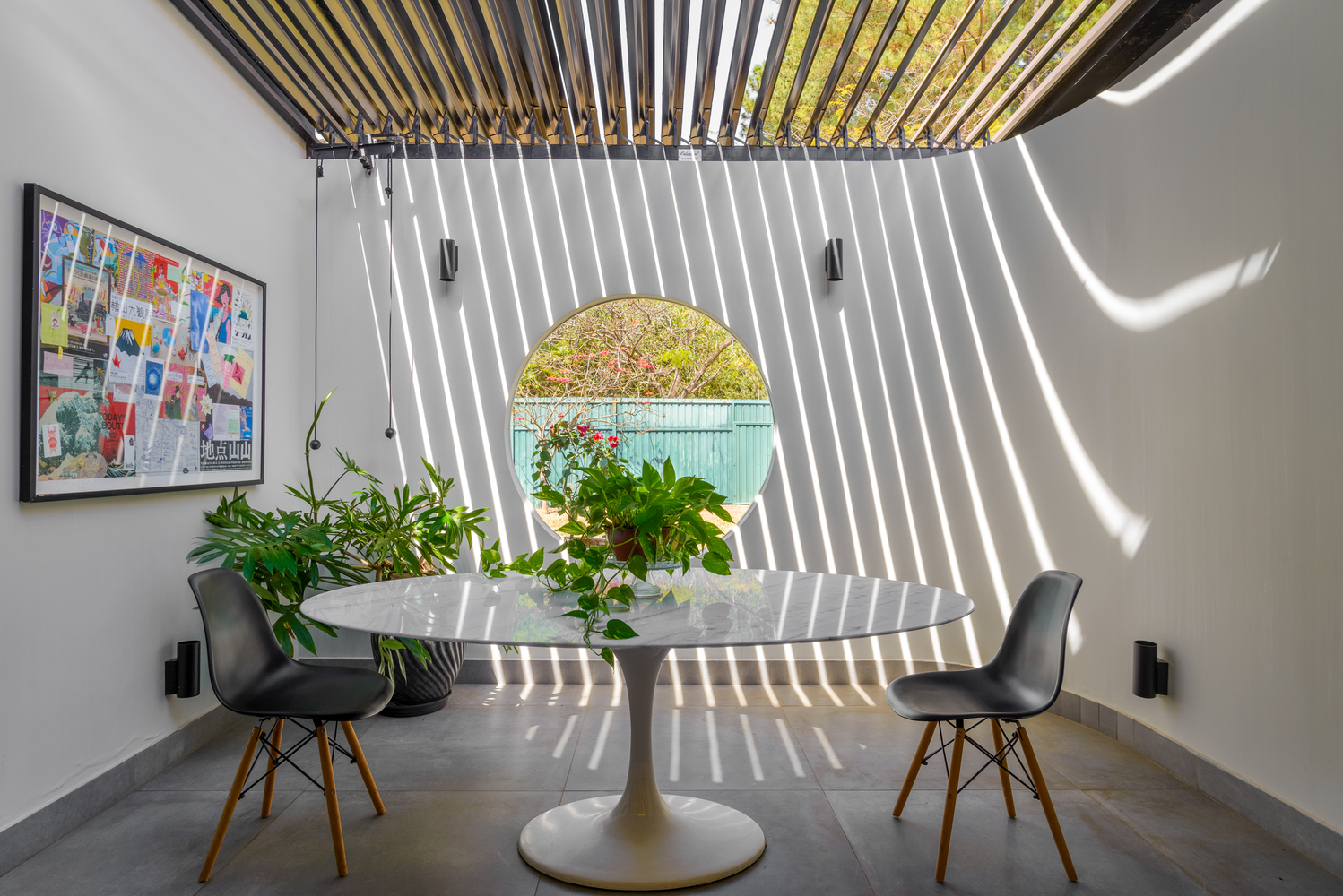 Dining nook with circular window and overhead louvers creating striped light patterns on white walls