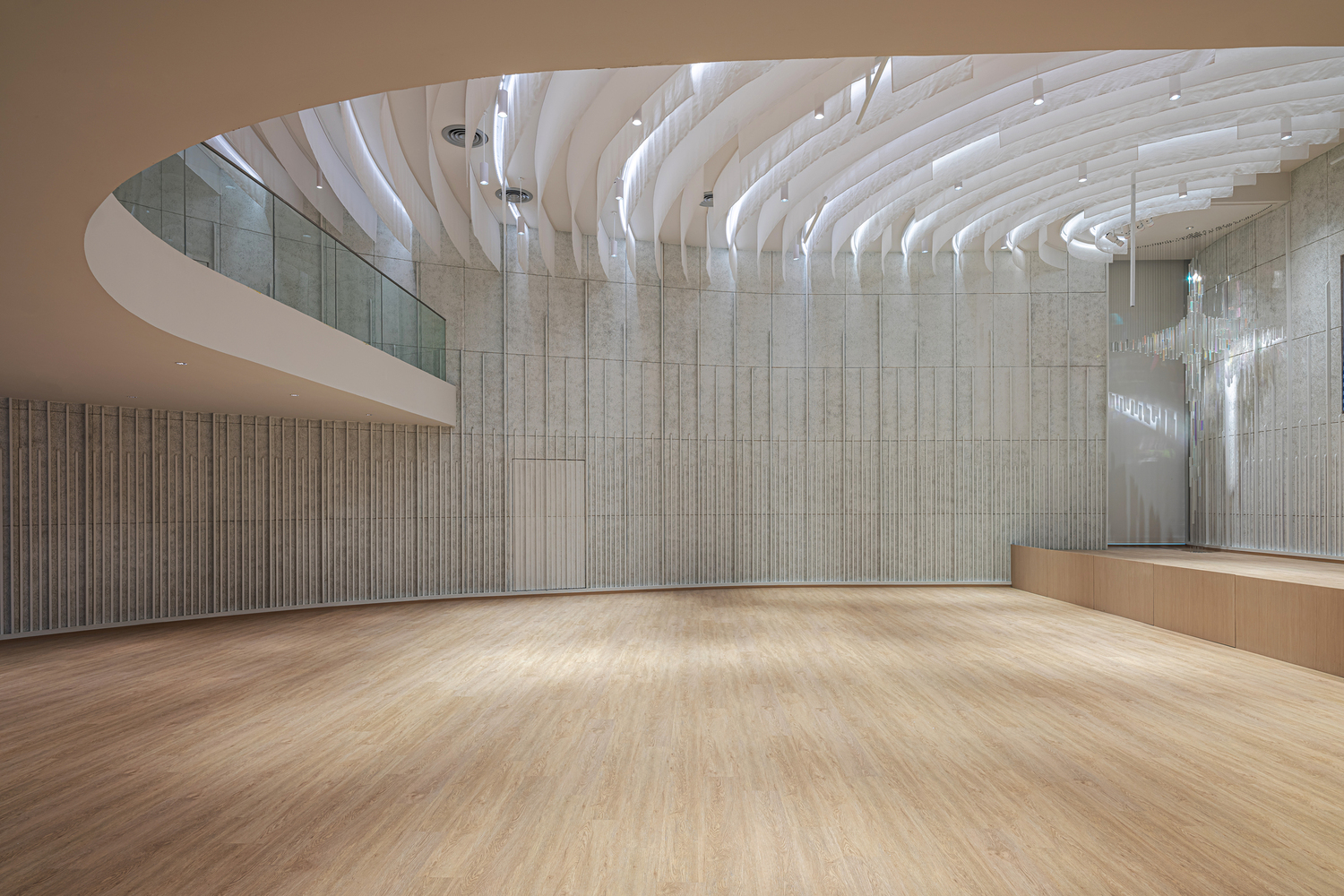 Interior hall with curved white acoustic ceiling baffles above timber-lined walls and polished wood flooring