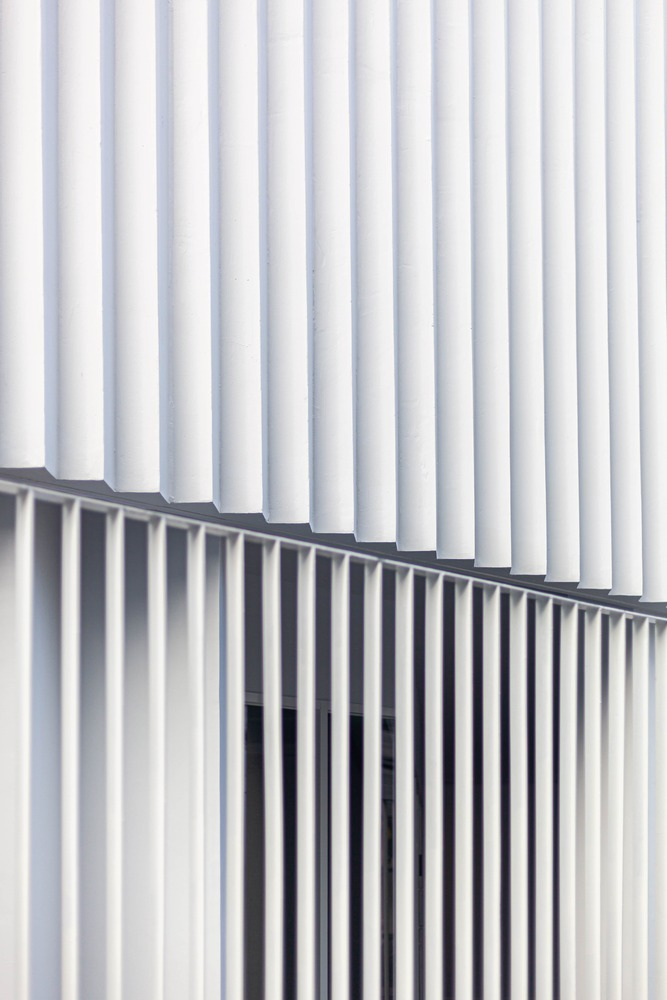 Close-up of white vertical metal fins meeting at a diagonal seam in soft daylight