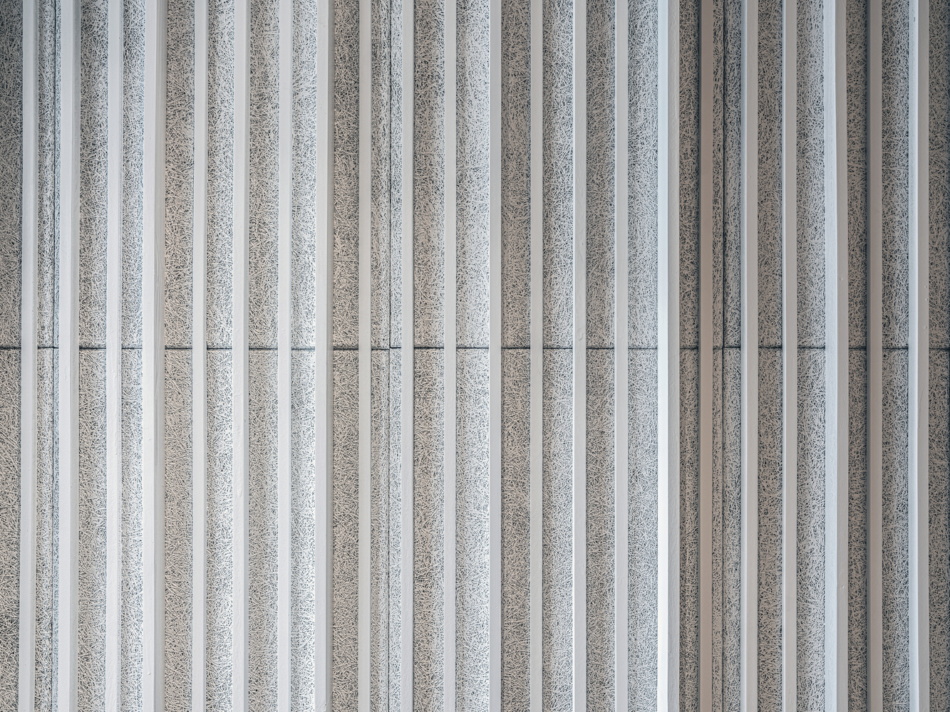 Facade detail showing alternating light and dark vertical concrete fins in overcast weather