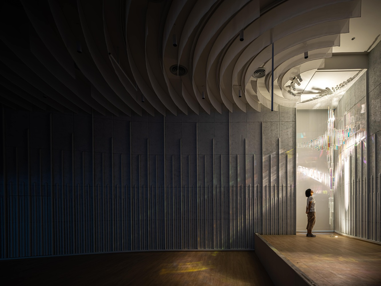 Interior hall with concentric curved ceiling ribs and a figure standing near a chandelier