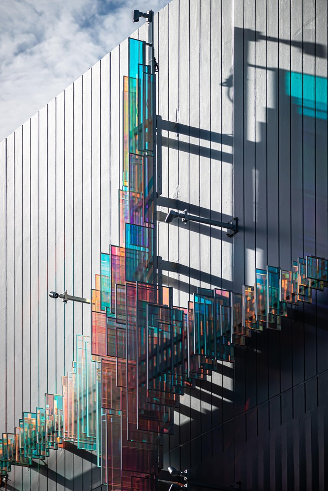 Exterior facade with white vertical fins and colorful glass panels projecting on horizontal arms