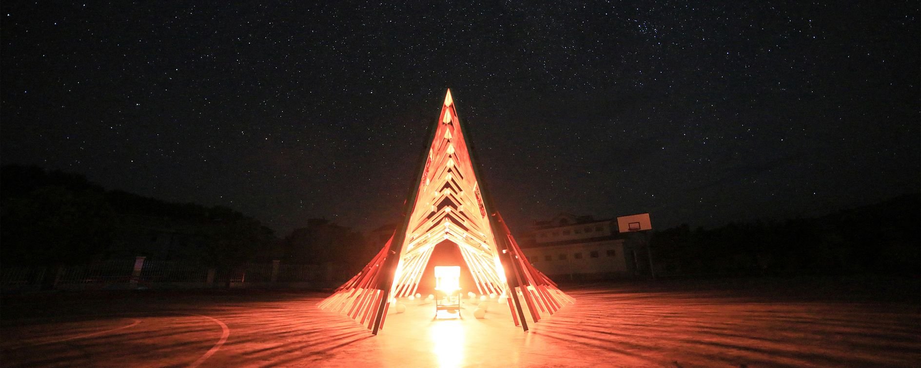 Hi Ladders High at night, a community-driven architectural marvel designed by children, illuminated under the starry sky.