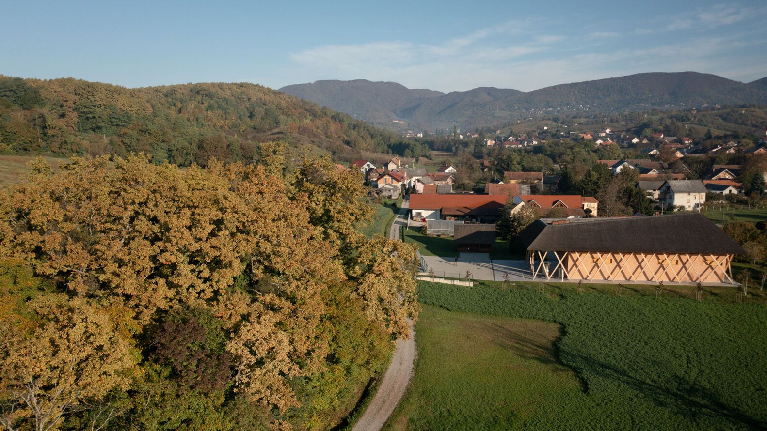 Aerial view of the curved timber lattice roof set among autumn trees and green fields
