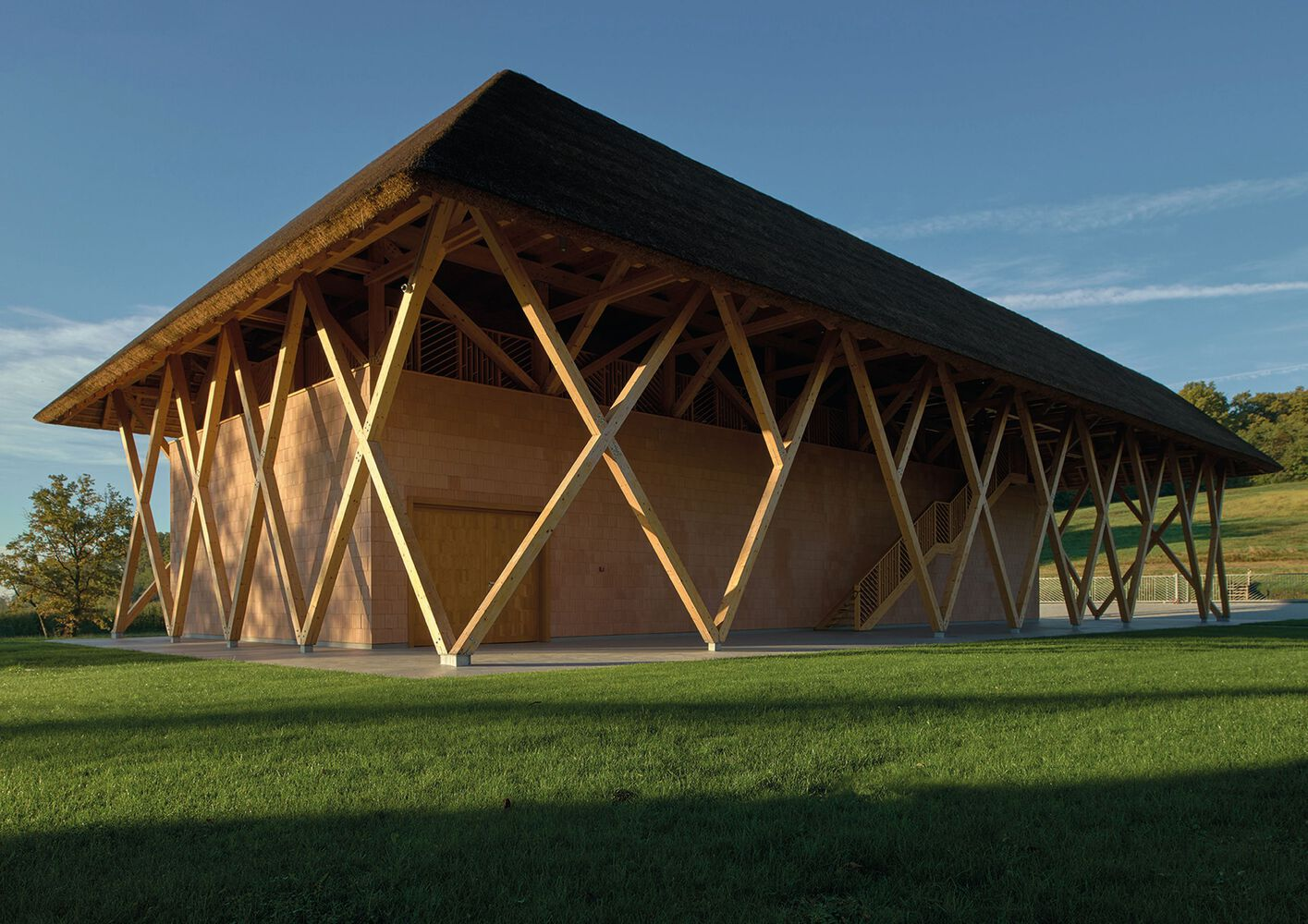 Exterior view of the timber lattice facade with diamond-shaped openings at sunset on a lawn