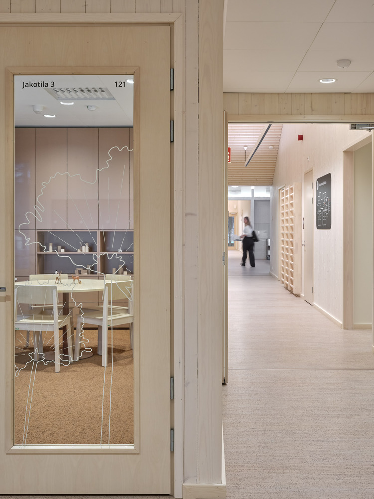 Glass door with etched tree motif and signage leading to a bright corridor