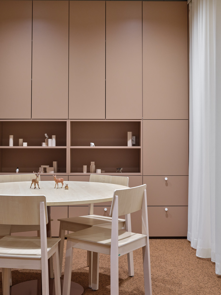 Activity table with toy animals beneath built-in birch cabinetry and open shelving