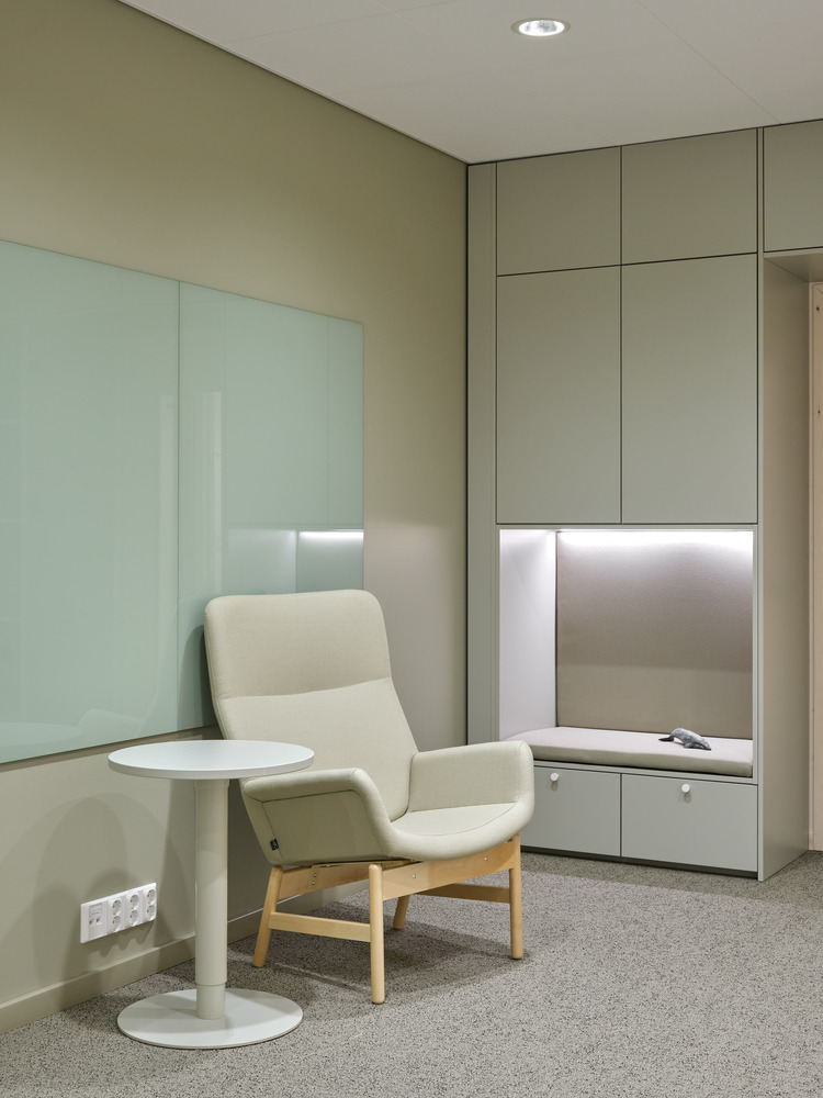 Corner seating nook with white armchair and round table beneath recessed downlight