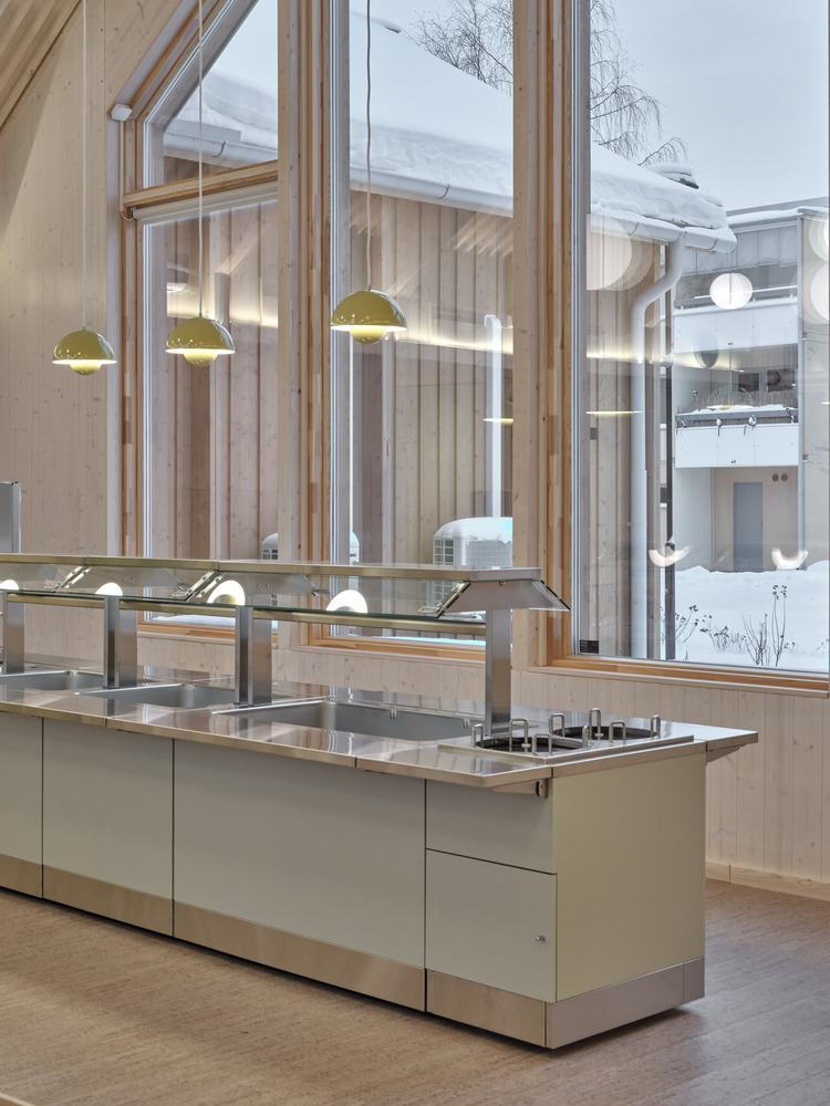 Double-height kitchen with pendant lights and full-height windows overlooking snowy courtyard