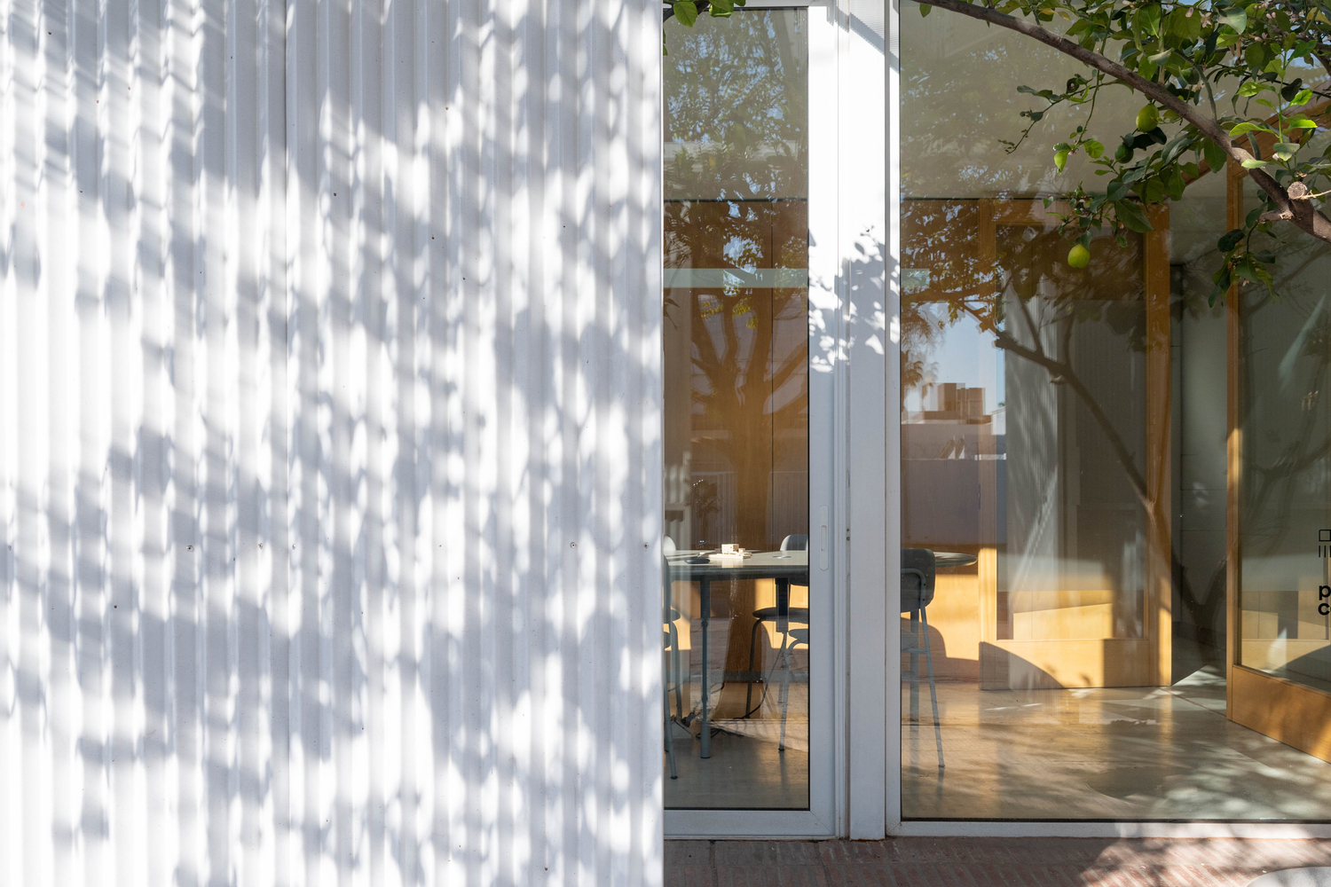 Perforated metal screen casting shadows beside glazed doors opening to the interior dining area