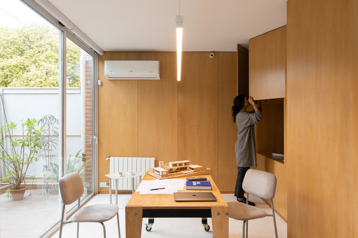 Workspace with timber walls and a mobile table looking onto a small planted terrace