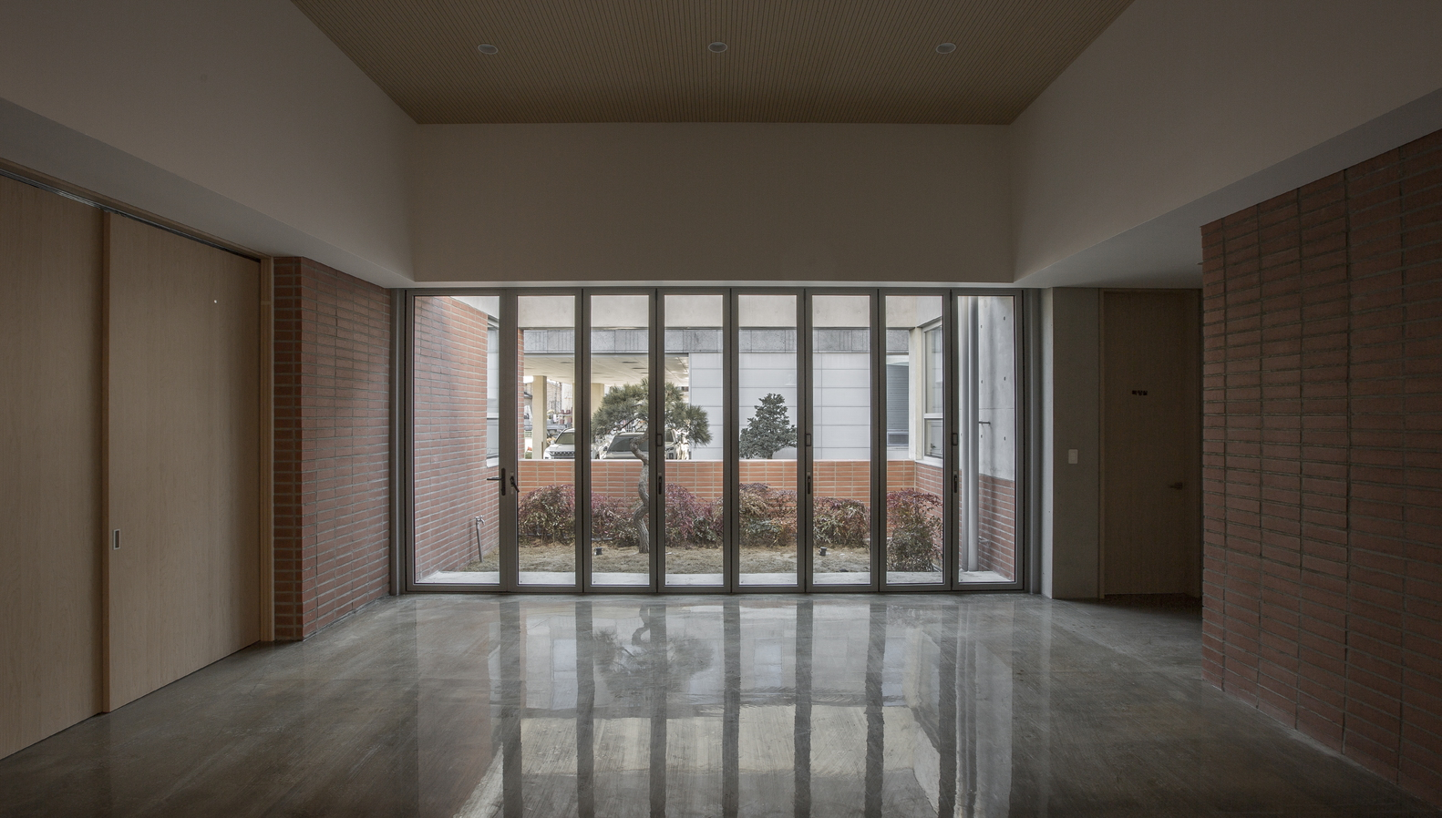 Interior space with polished concrete floor reflecting light from the glazed courtyard wall