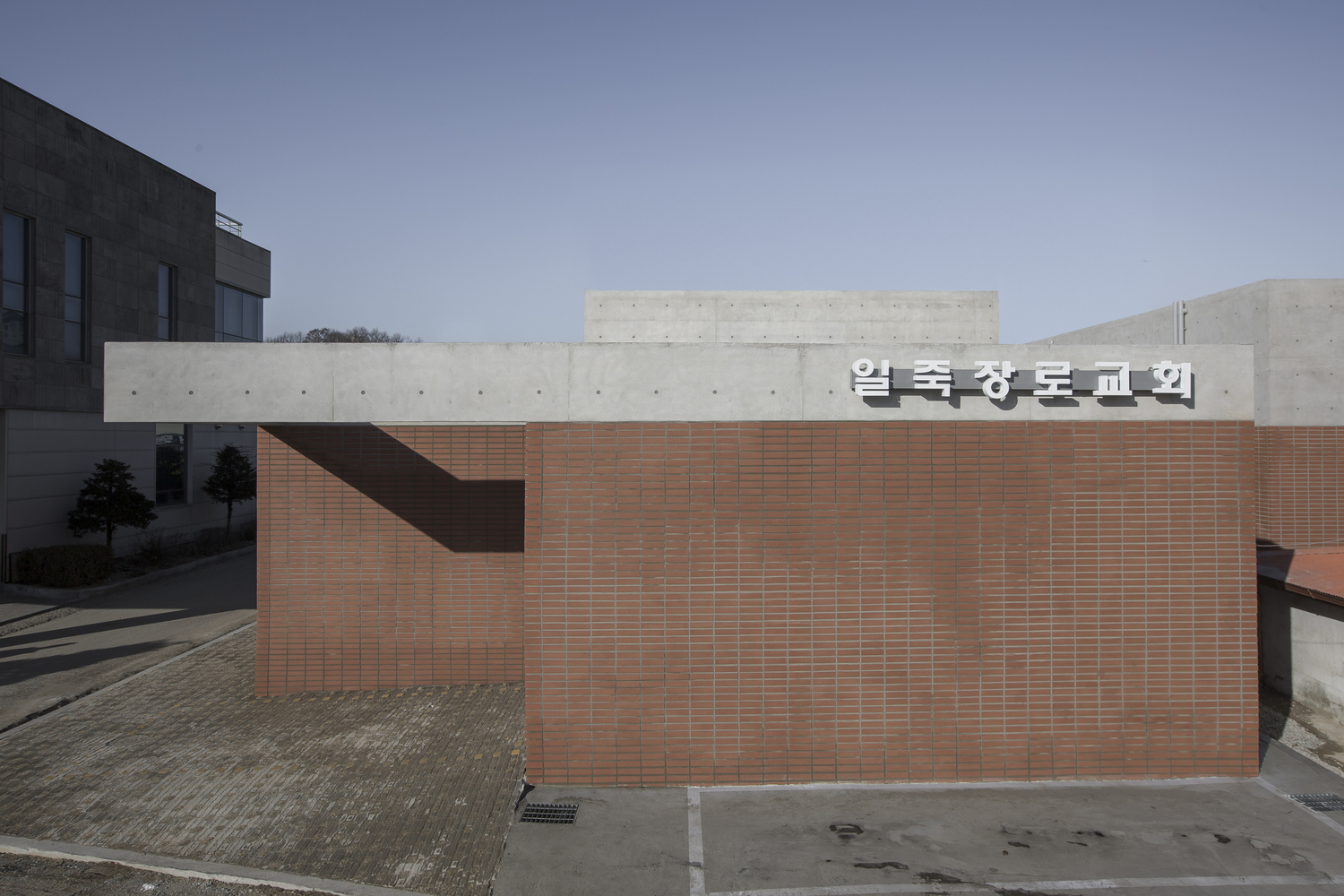 Entry view showing the red brick base topped by concrete walls with signage