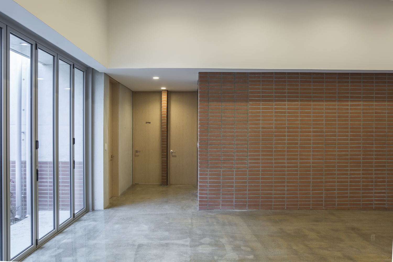 Open interior space with terracotta brick screen wall and sliding glass doors to an exterior stair
