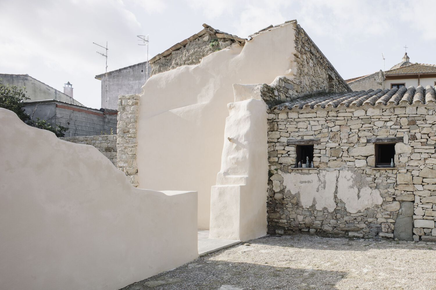 Junction of a smooth stucco wall and a rough stone wall with two small window openings