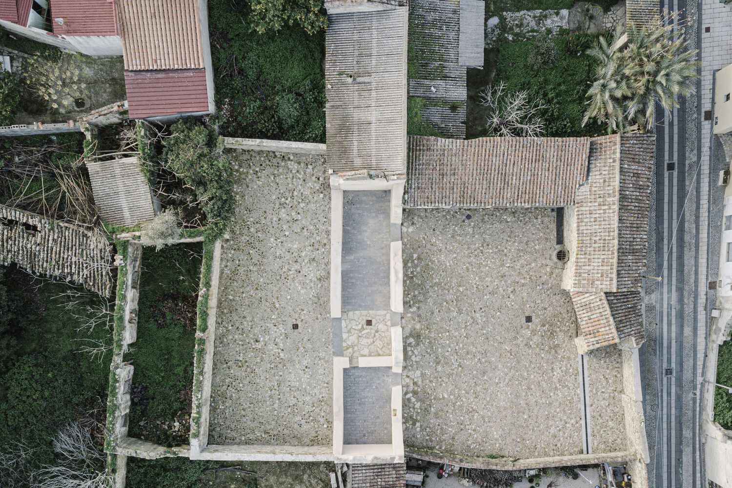 Aerial view of a gravel-surfaced rooftop terrace with skylights surrounded by neighboring residential buildings
