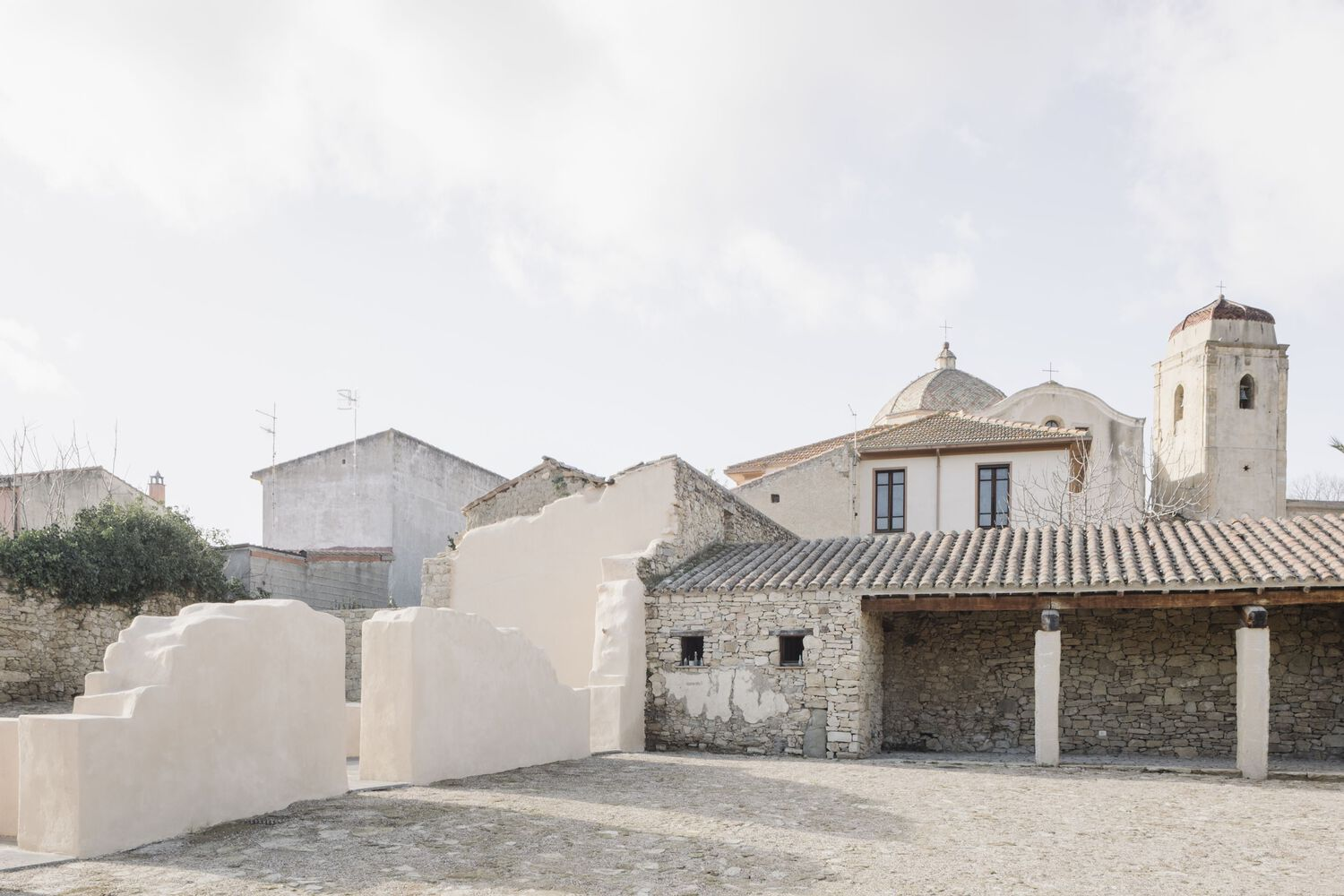 Rooftop terrace with curving plastered forms overlooking a church dome and historic town rooftops