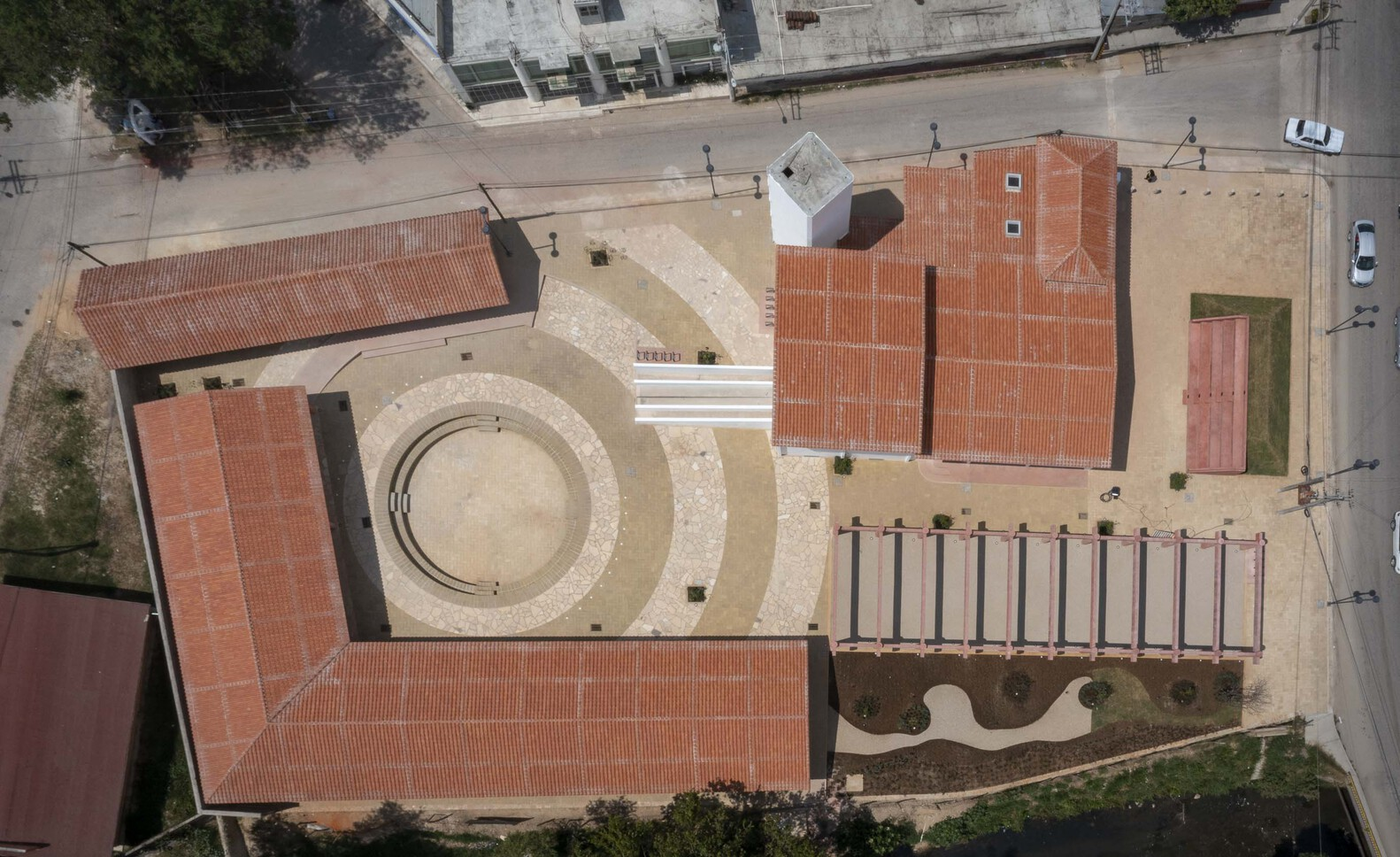 Aerial view of clay tile roofs surrounding circular courtyard fountain and adjacent colonnade