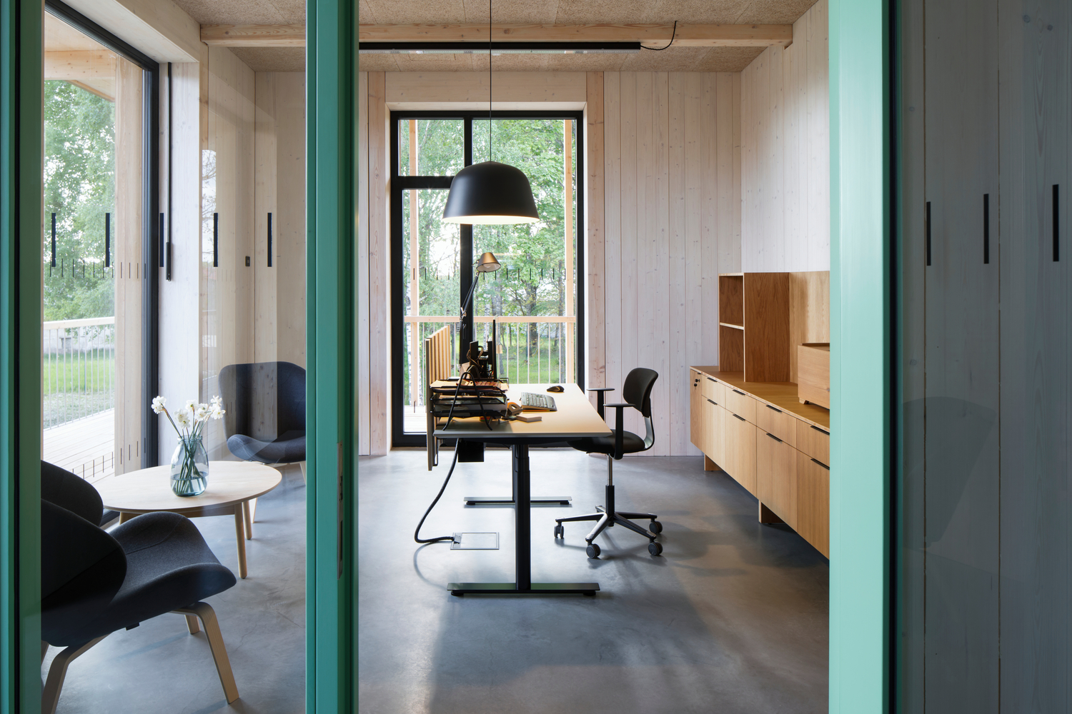 Workspace framed by teal columns with whitewashed timber walls and light oak built-in cabinetry