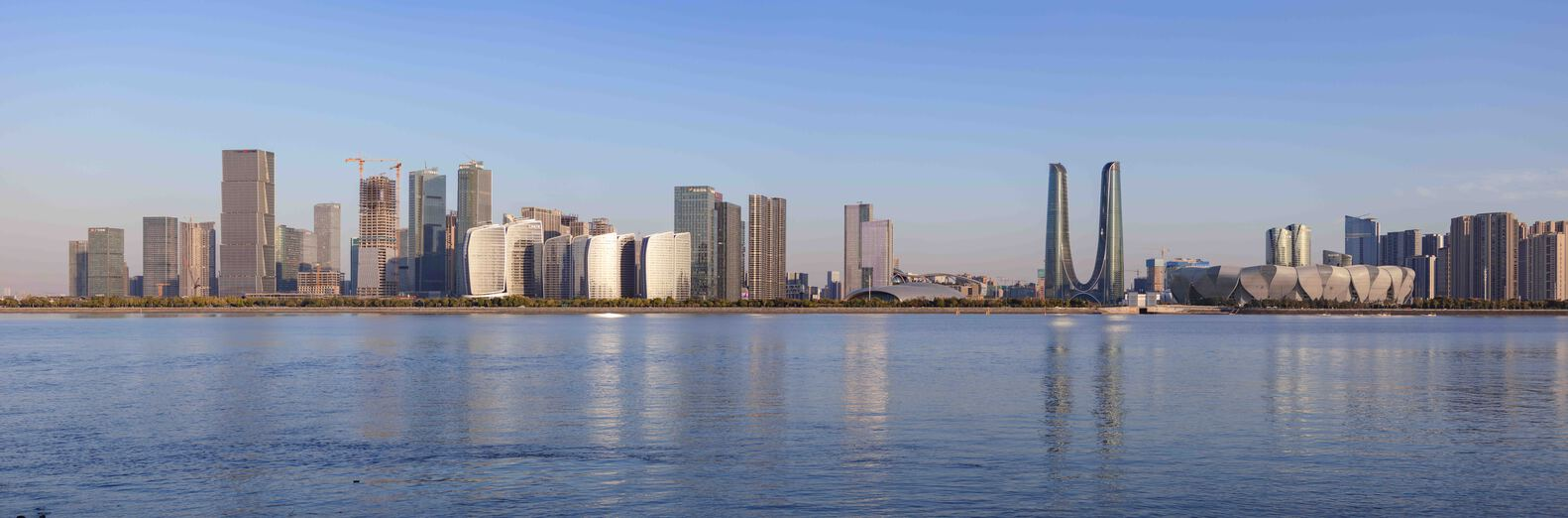 Waterfront panorama of skyline with twin loop towers reflected in calm water