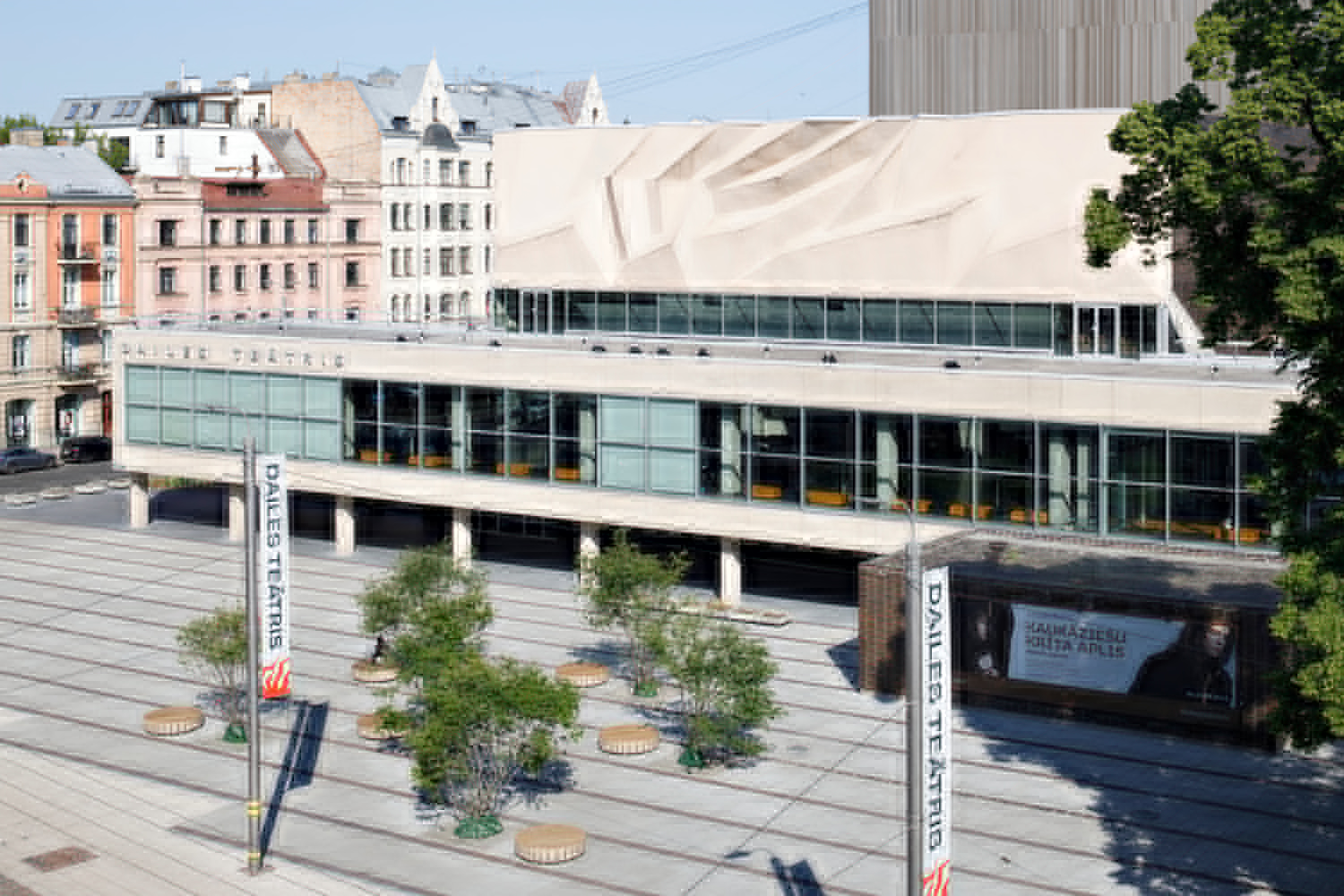 Two-story glass facade with concrete columns and pleated canopy above the plaza