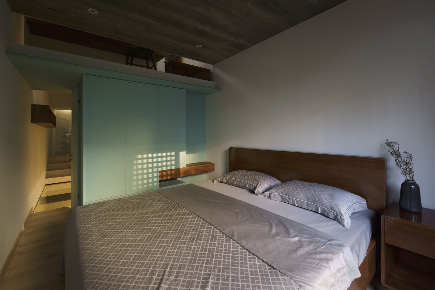 Bedroom with timber headboard, mint green built-in wardrobe, and dark concrete ceiling