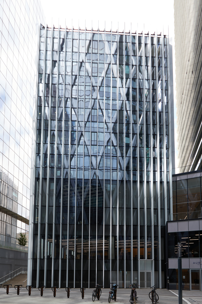 Glass and metal facade with diagonal bracing pattern viewed from the plaza with pedestrians below