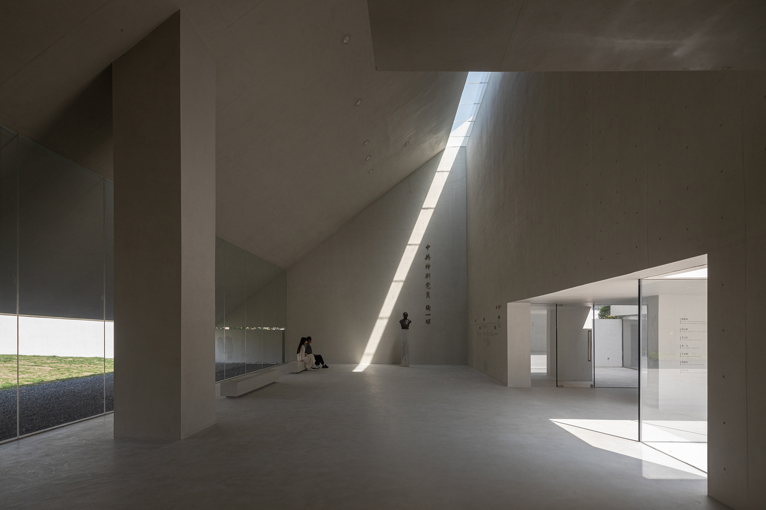 Interior gallery with concrete walls and a narrow skylight casting sharp daylight across the floor