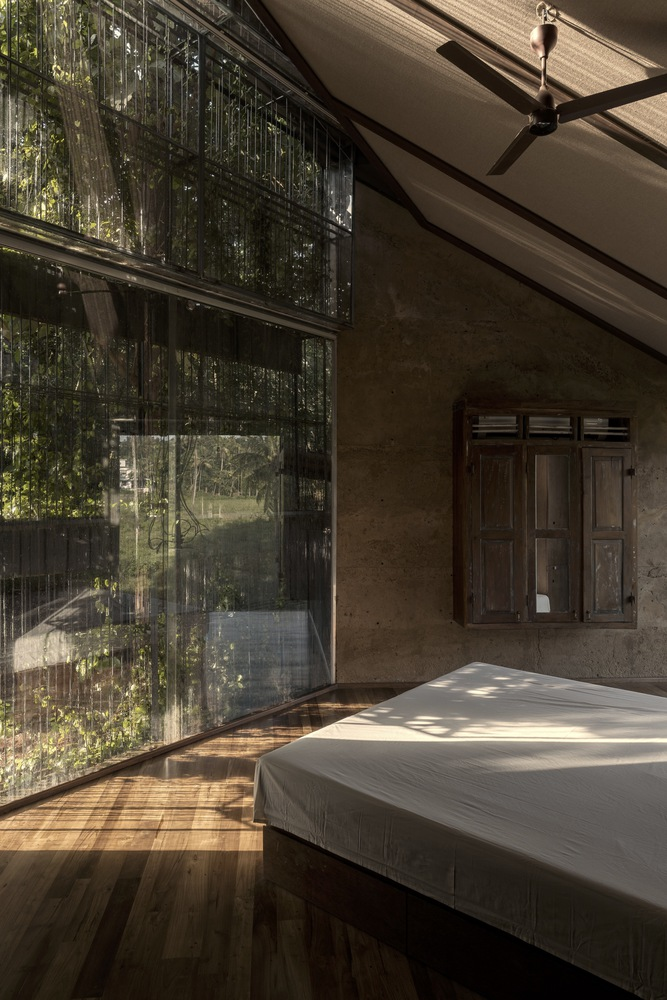 Bedroom with floor-to-ceiling glazing and wire mesh screens framing views of dense vegetation outside