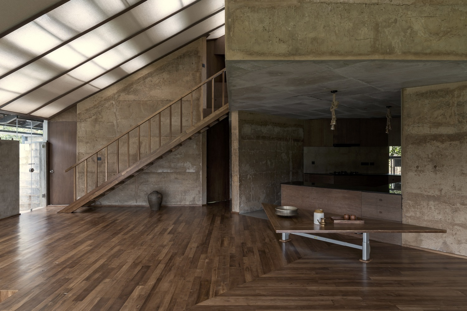 Open living space with timber staircase and translucent roof panels casting soft light across wood floors