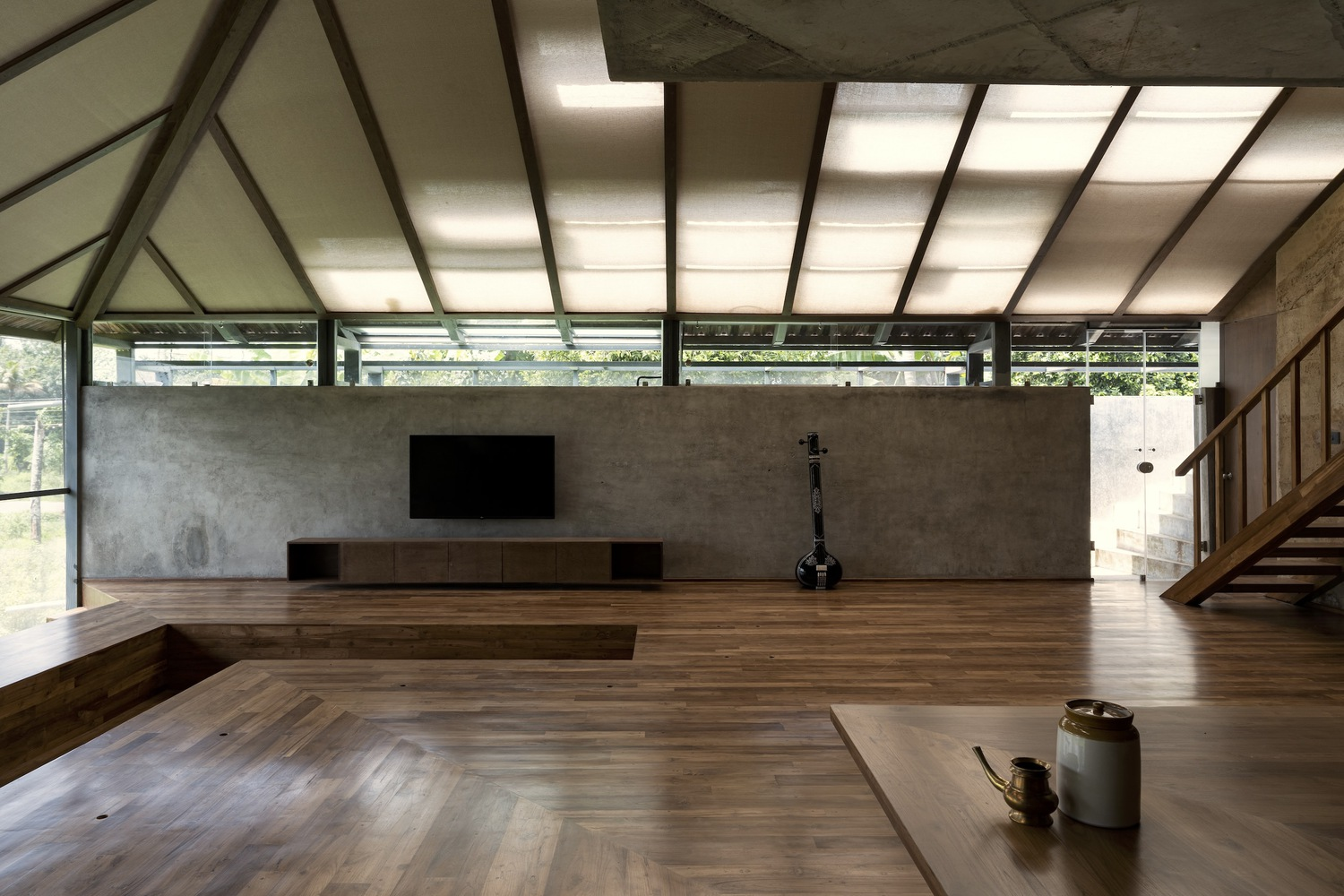 Living room with sloped translucent roof and clerestory windows above exposed rammed earth walls
